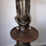 Sculpture contemporaine signée par l’artiste français Serge Roca, réalisée à partir d’éléments métalliques assemblés et détournés. L’œuvre se distingue par son esthétique brute et expressive, mêlant puissance industrielle et inspiration ethnique. Le travail des volumes, des textures et des soudures apparentes confère à la pièce une forte présence sculpturale. Les nuances métalliques patinées renforcent son caractère unique et contemporain. Une création singulière, idéale dans un intérieur contemporain, une galerie ou un espace au style industriel et artistique. Dimensions: l. 51 cm x prof. 60 cm x h. 210 cm Métal assemblé et travaillé